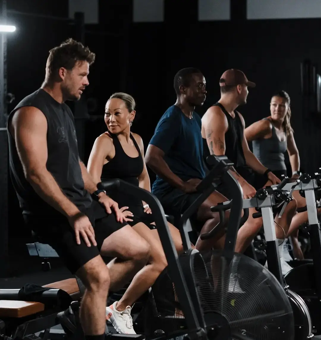 Members working out in a group conditioning session on the bike ergs